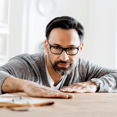 Mann mit Brille schaut selbstbewusst in die Kamera