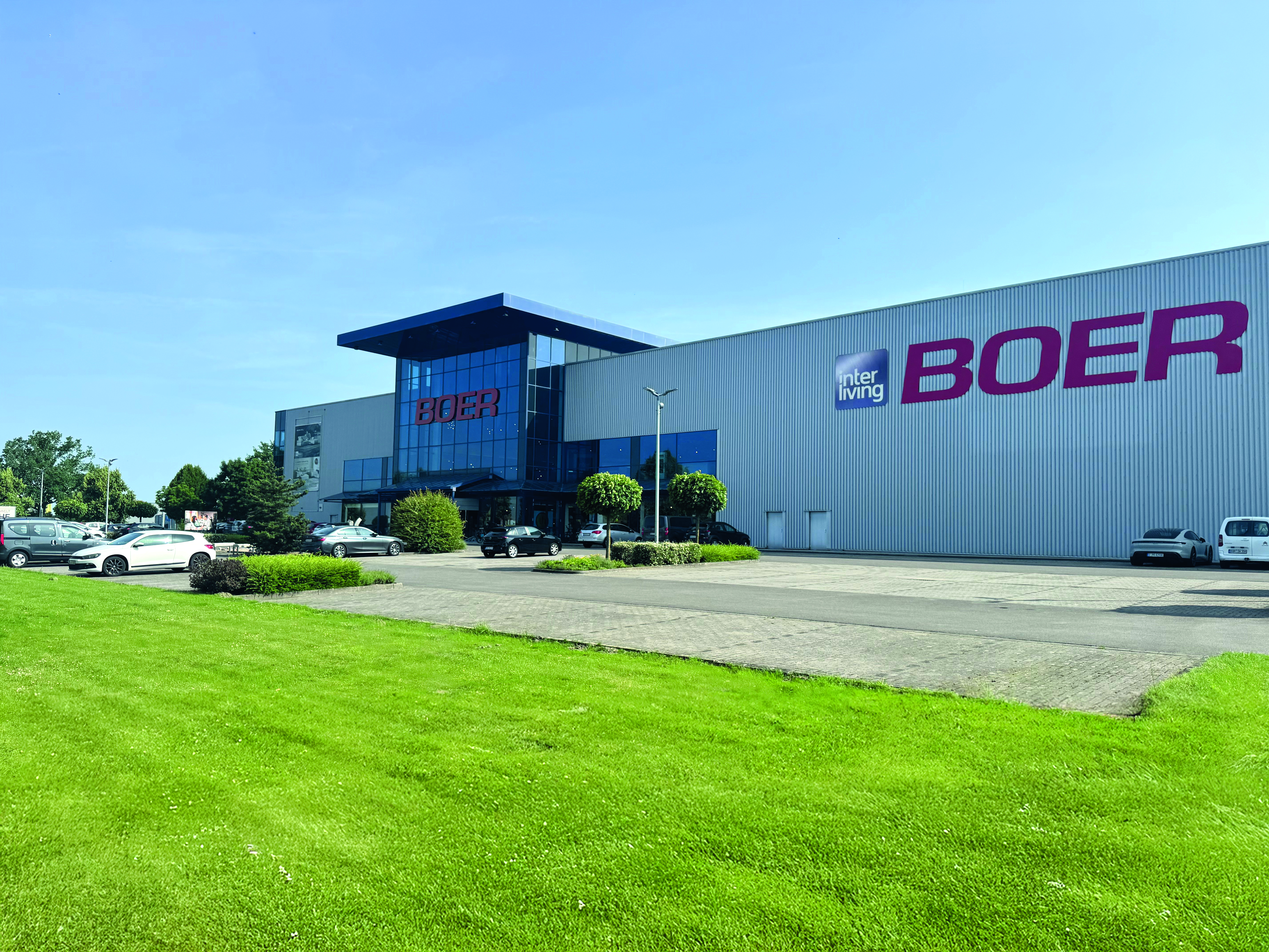 Großes Industriegebäude mit „BOER“-Beschilderung und geparkten Autos
