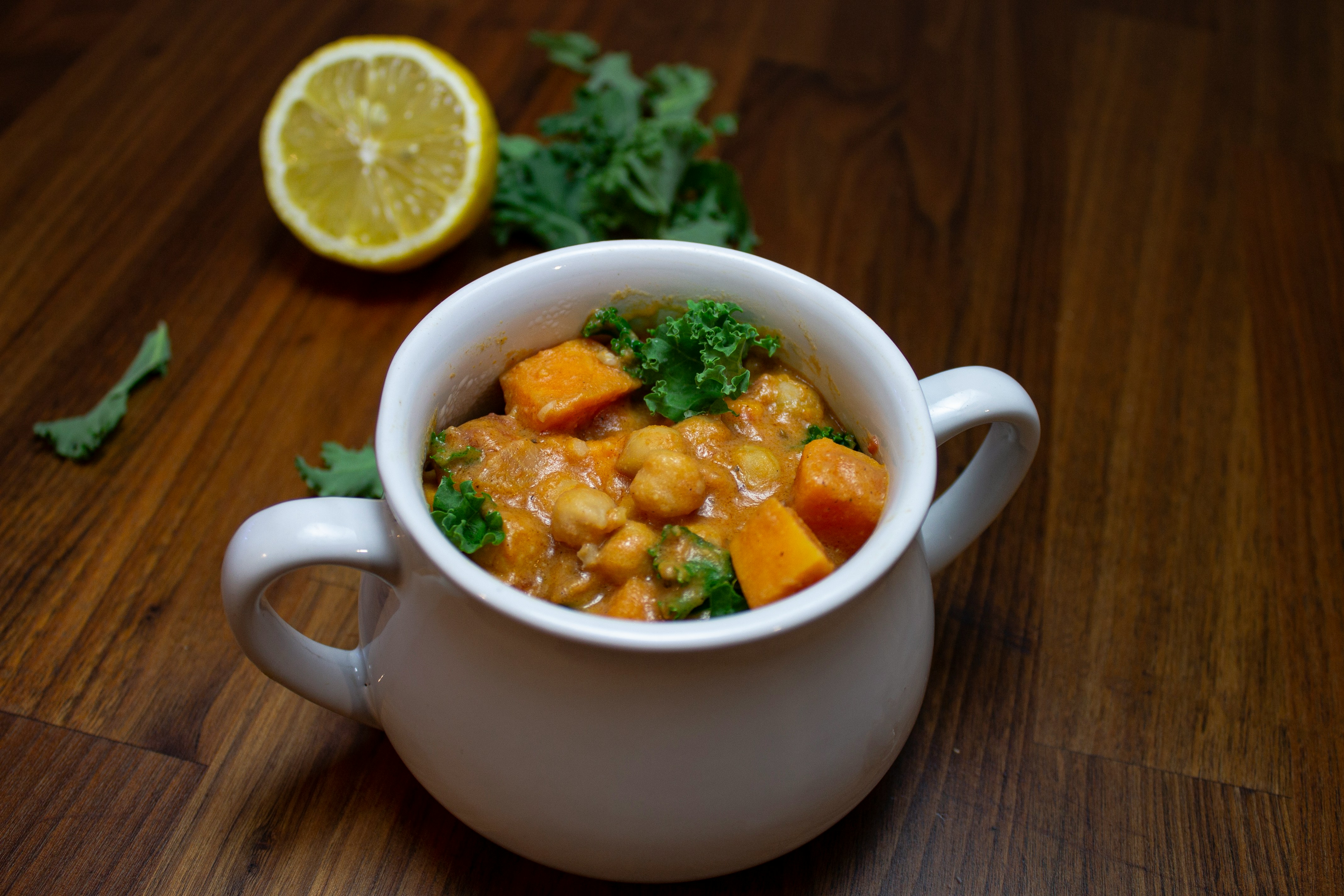 Herzhafte Meal-Prep-Bowl mit Süßkartoffeln, Kichererbsen und Grünkohl auf einem Holztisch