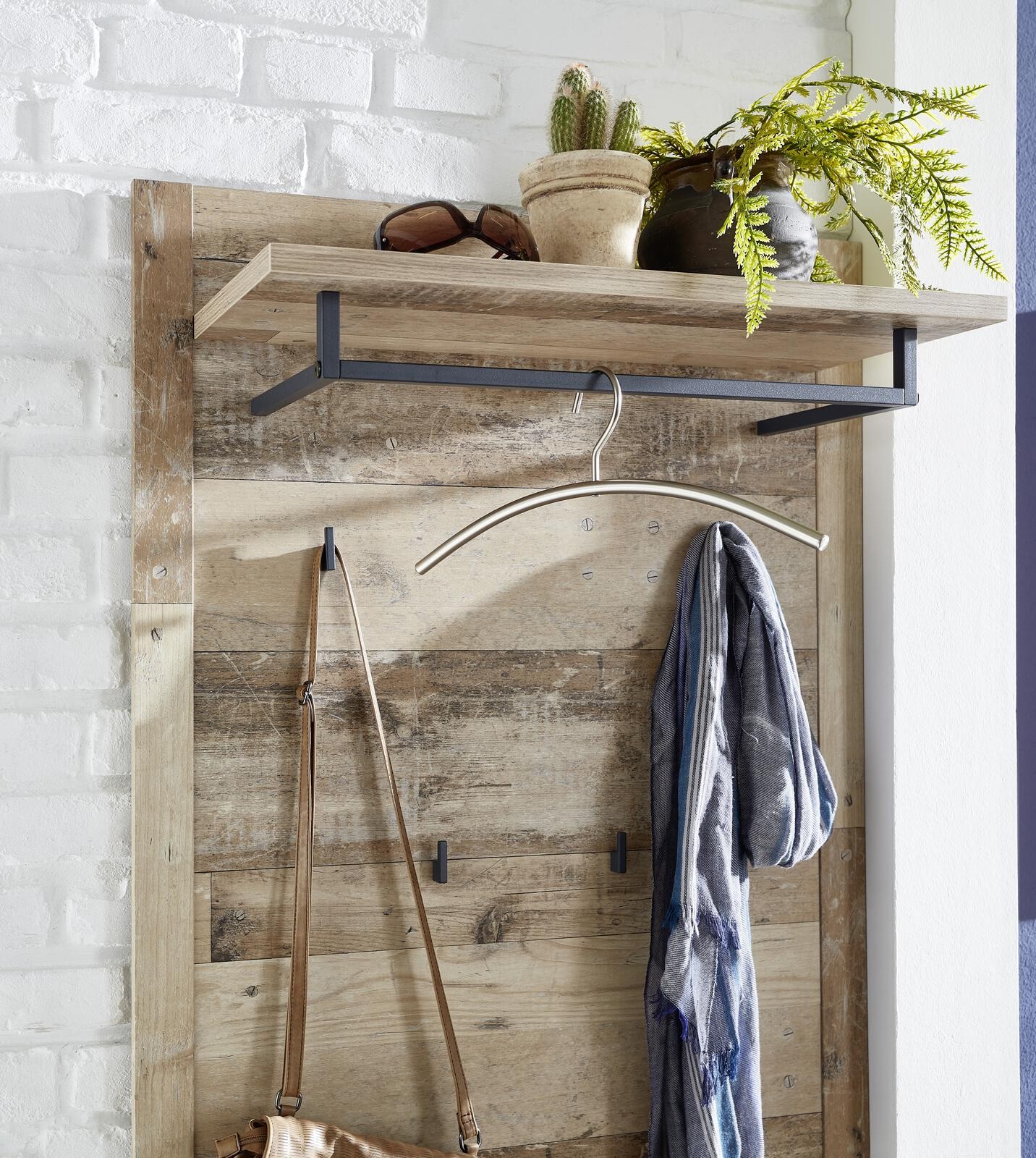 Wall mounted storage shelf with minimalist decor: plants, sunglasses, scarf, and bag.
