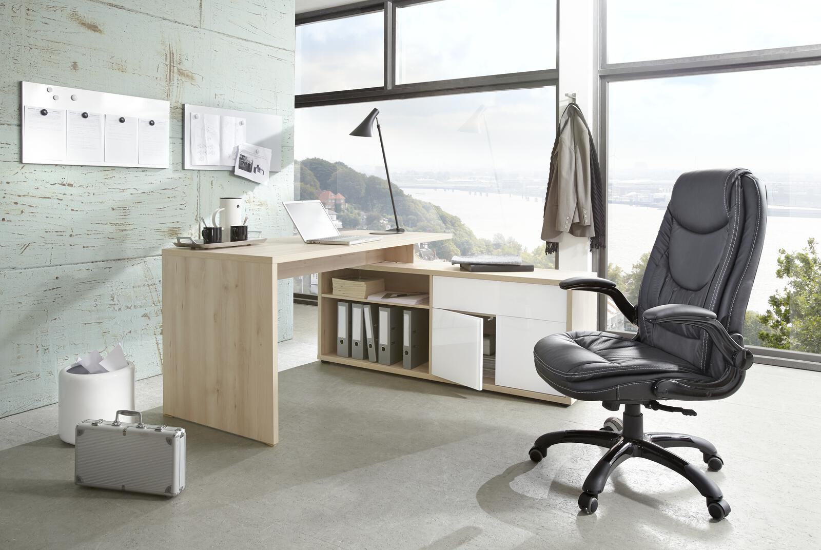 Modernes Büro mit hellem Holzschreibtisch, schwarzem Bürostuhl und großem Fenster