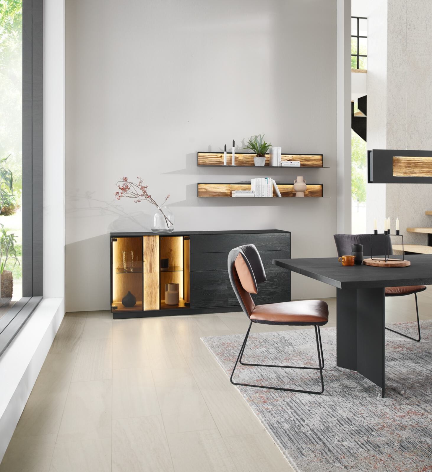 Modernes Esszimmer mit Esstisch, Stühlen, Sideboard und Regalen in dunklem Holz und hellen Tönen.