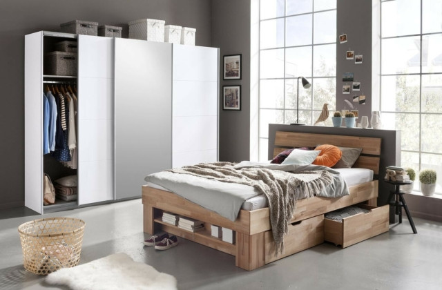Modernes Schlafzimmer mit großem Kleiderschrank, Holzbett und viel Tageslicht.