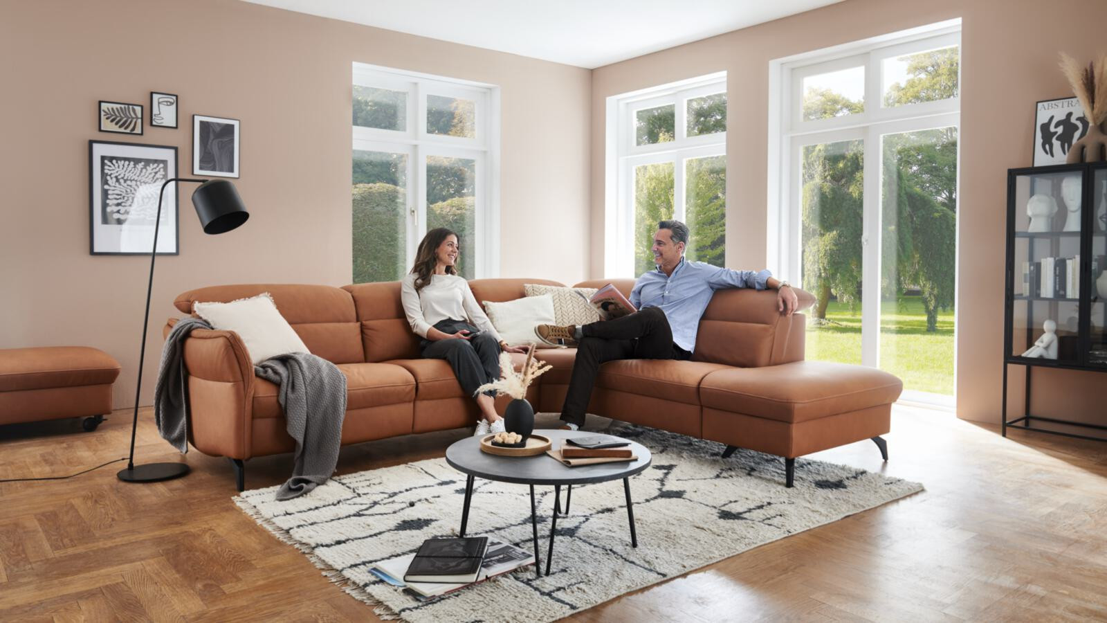 Modernes Wohnzimmer mit braunem Ledersofa, Paar entspannt. Hell und freundlich.