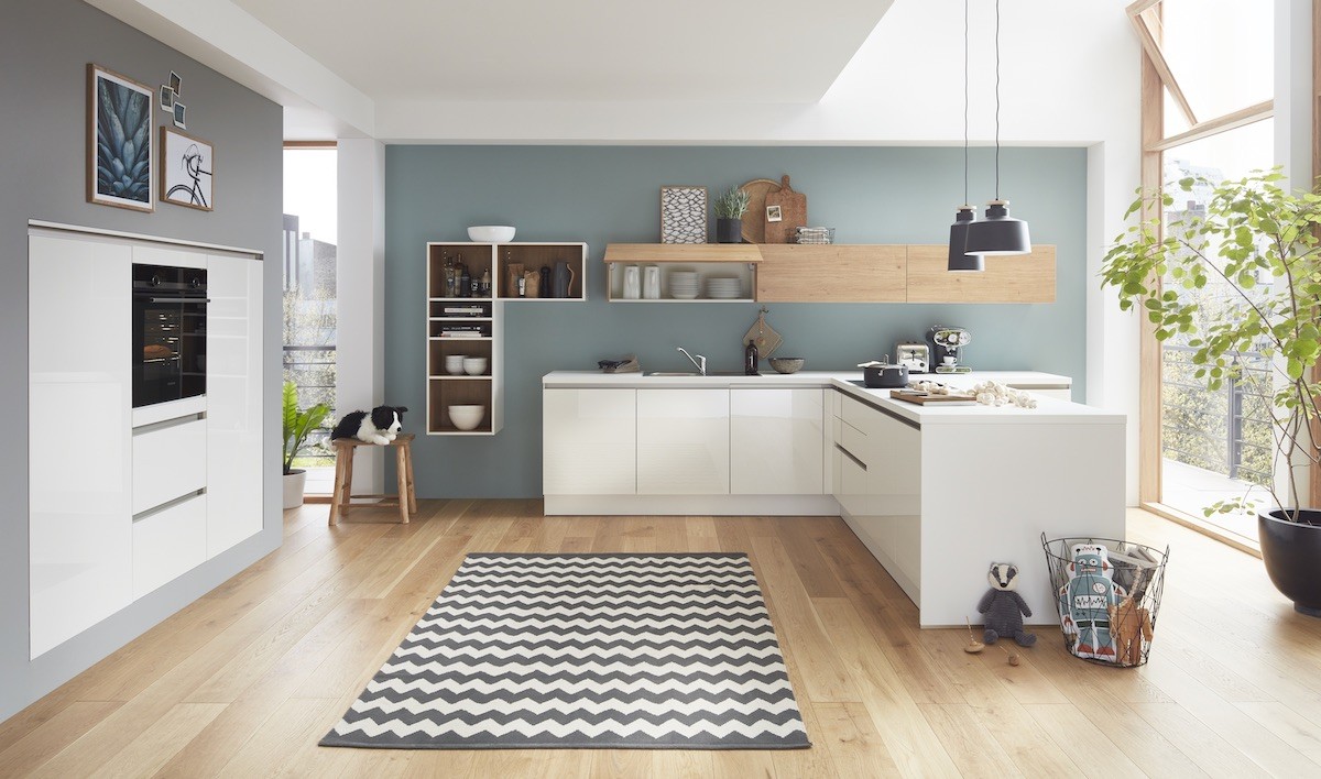 Moderne Küche mit weißen Schränken, Holzboden und blaugrüner Wand.