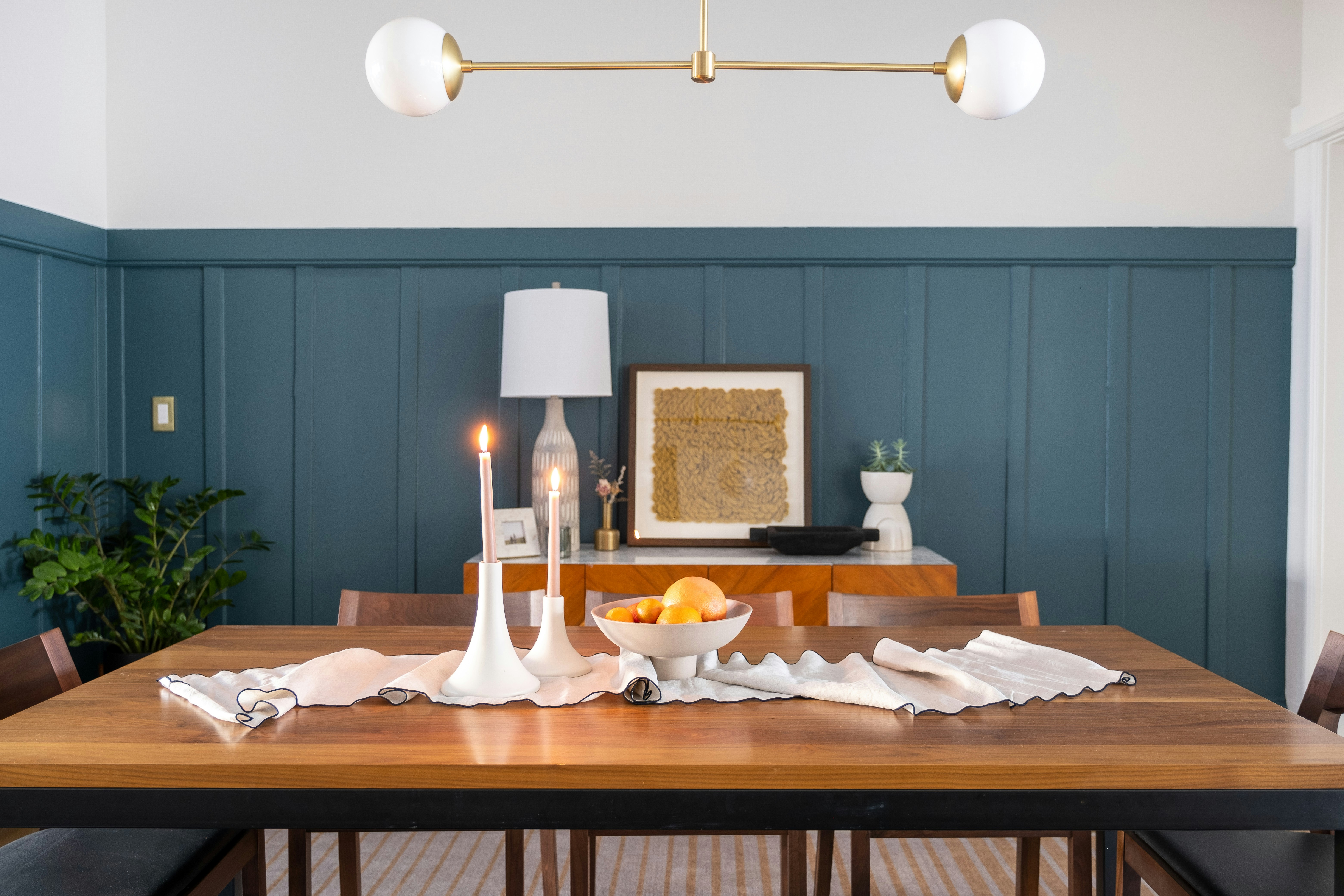 Elegantes Esszimmer mit Holztisch, Kerzen und Obstschale.