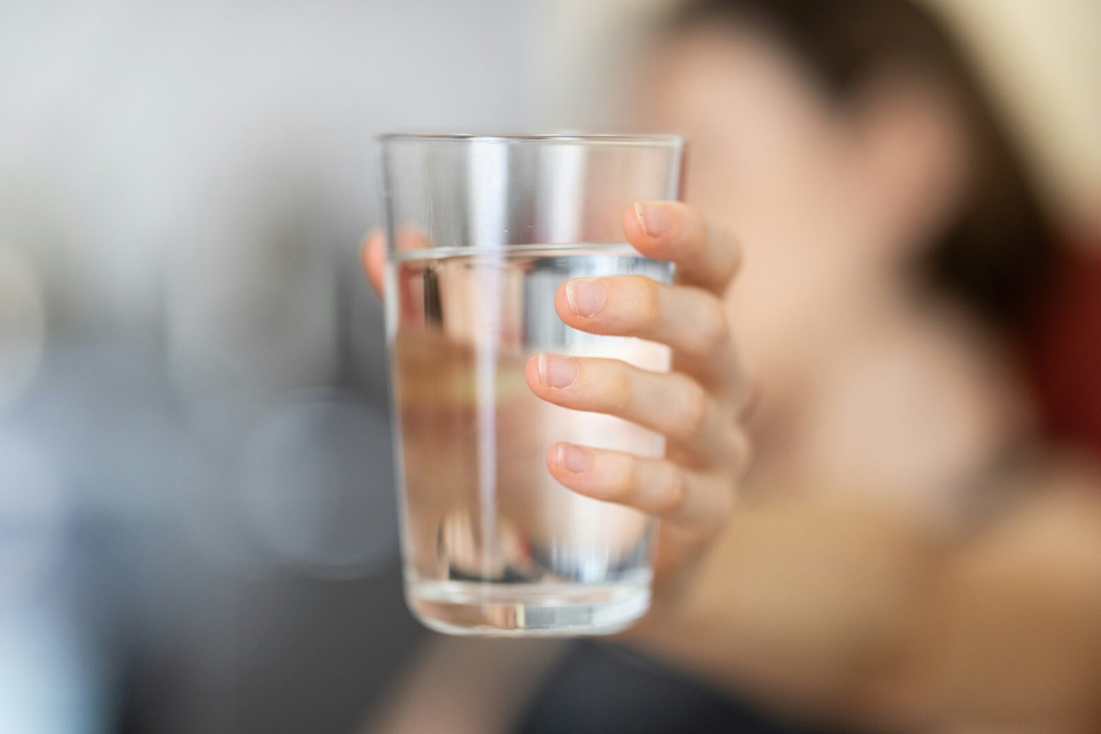 Hand hält Glas Wasser. Gesunde Vorsätze für das neue Jahr – Ernährung.