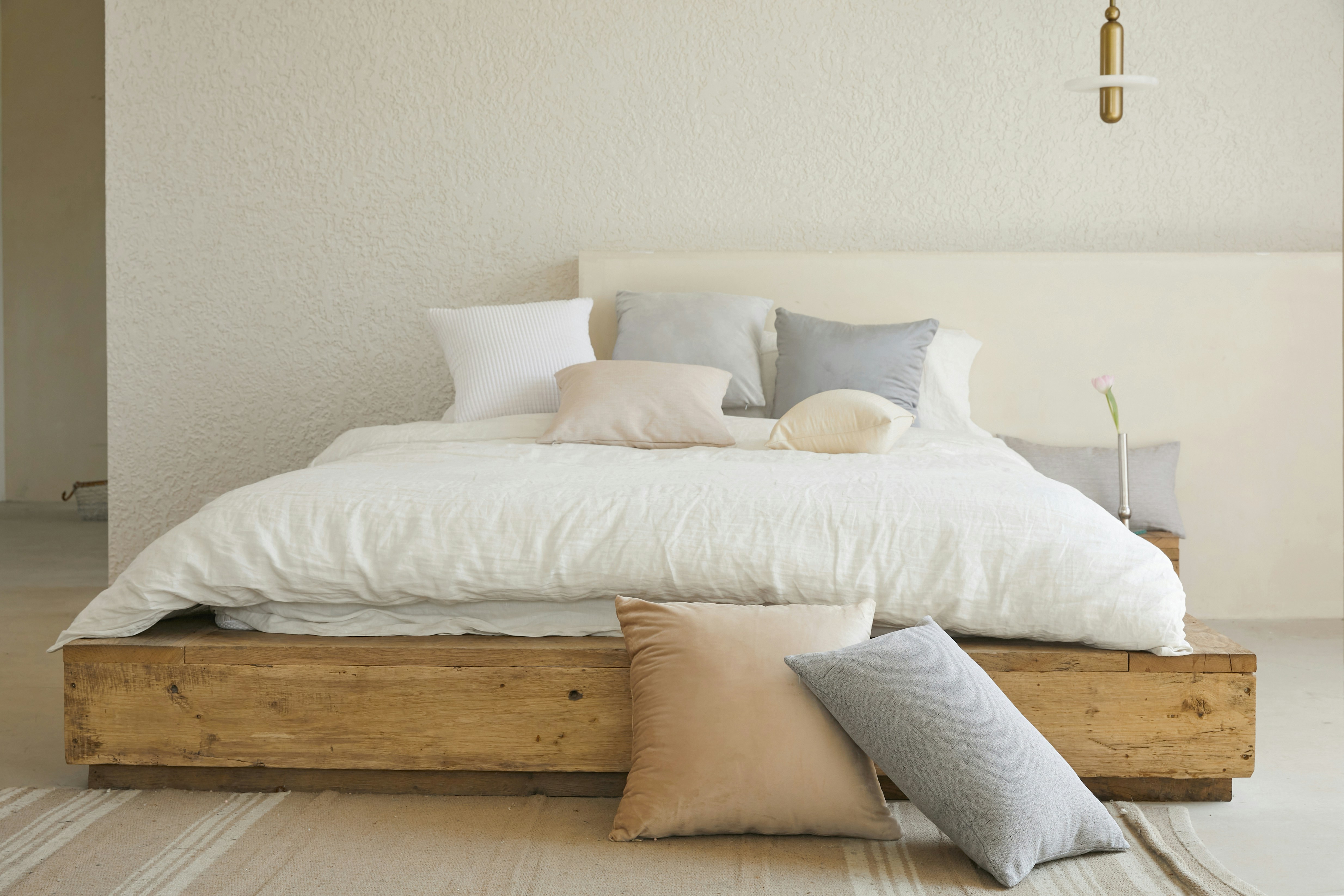 Schlafzimmer-Check: Gemütliches Bett mit Kissen in neutralen Farben vor strukturierter Wand.