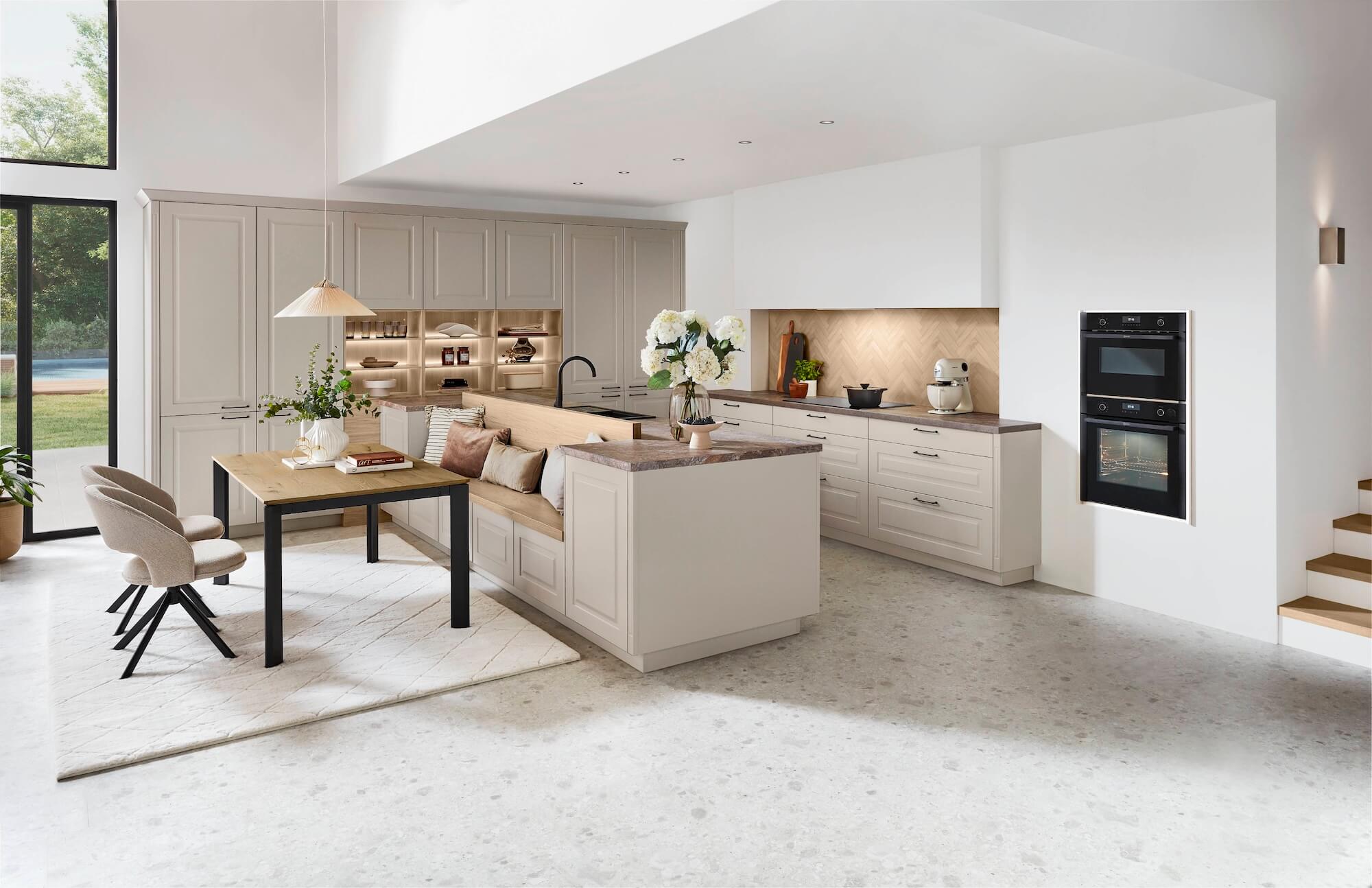 Moderne, helle Küche mit Kochinsel, Essbereich und Einbauschränken in Beige.