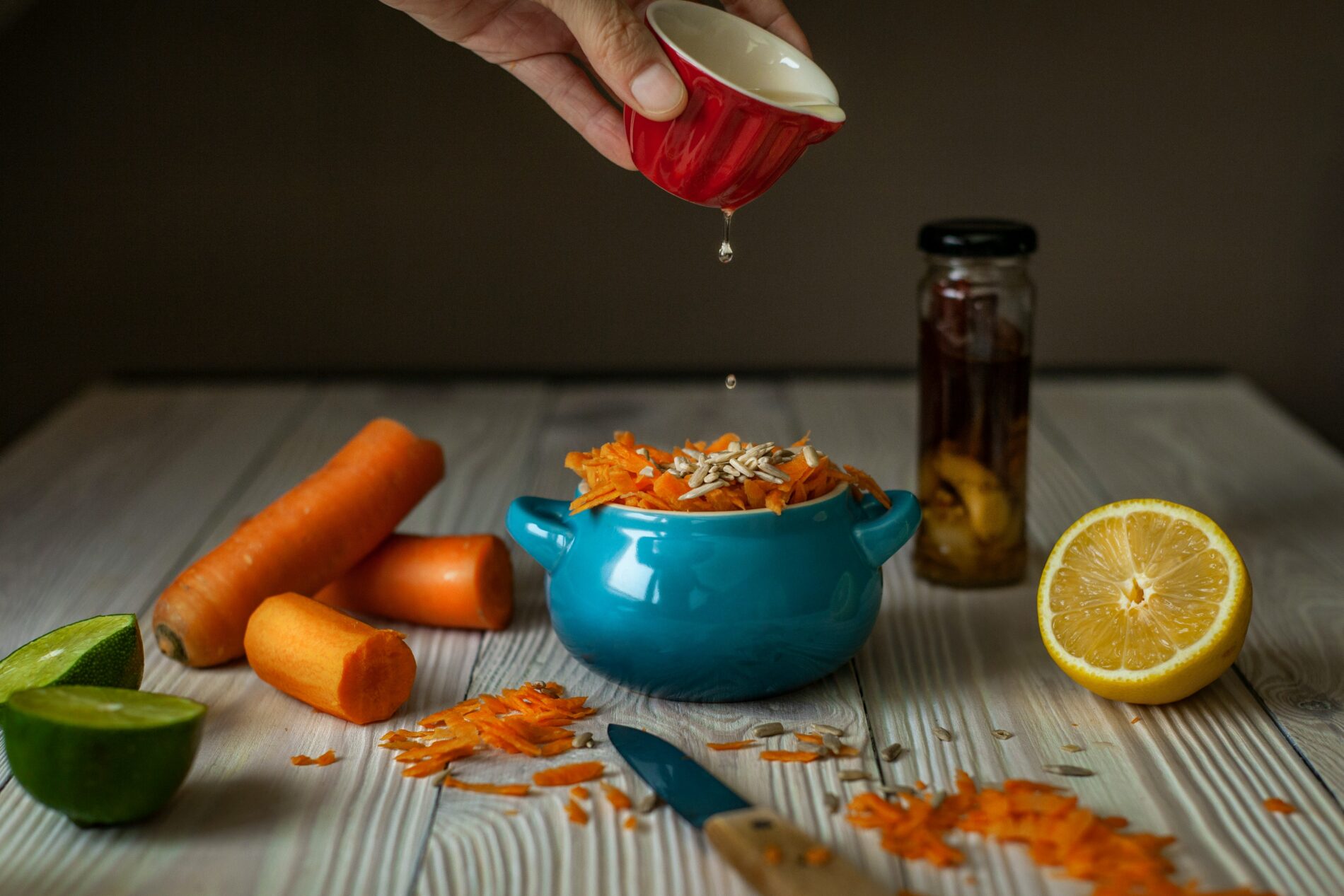 Karottensalat wird angemacht, Zitrone, Limette, saisonales Gemüse für gesunde Rezepte.