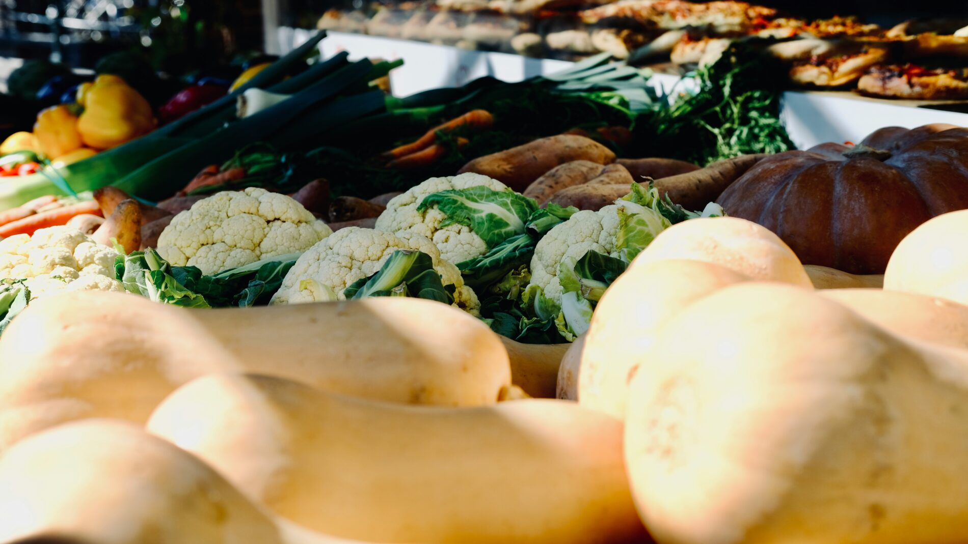 Saisonales Gemüse: Kürbisse, Blumenkohl, Karotten auf einem Marktstand.