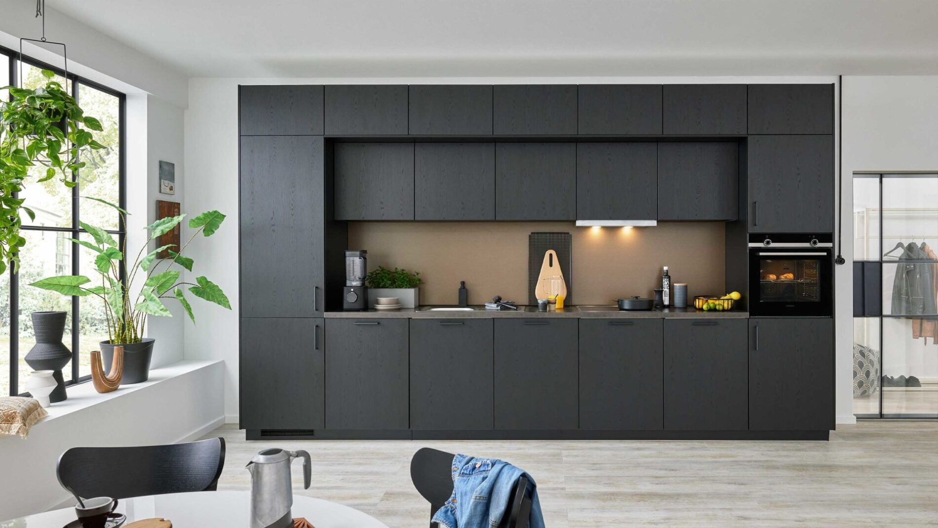 Moderne schwarze Küche mit integrierten Geräten und Pflanzen