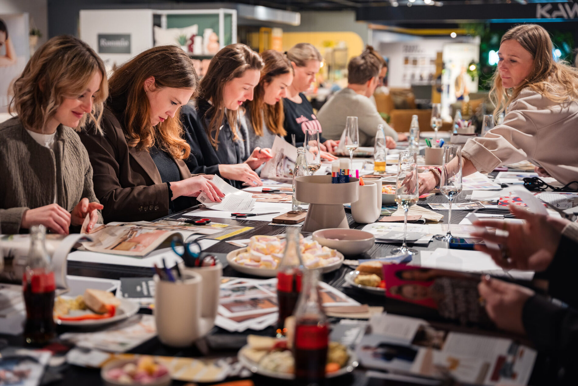 Teilnehmerinnen gestalten Moodboards beim Workshop in der Ausstellung von Interliving Möbel Boer